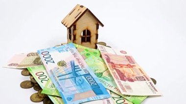 Rus rublesinden dökülen kağıt paralar ve bozuk paraların üzerinde ahşap bir ev.