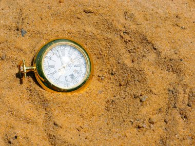 Altın bir çantanın içindeki antika bir cep saati bir gemi enkazı sırasında kumların üzerinde yatıyor.