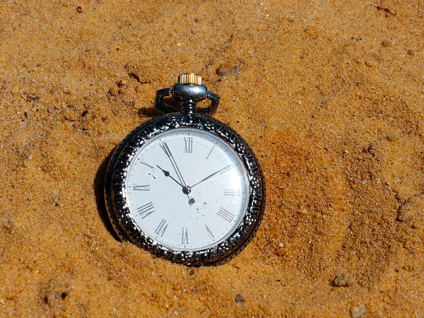 vintage antique pocket watch lies on the sand as a symbol of the passage of time