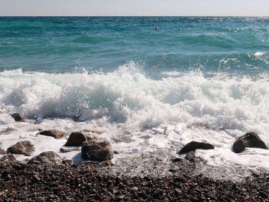 Deniz suyu dalgaları ve kayalık çakıl taşı plajı.