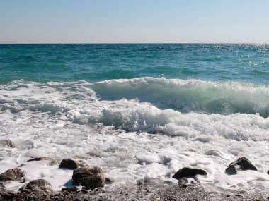 Deniz suyu dalgaları ve kayalık çakıl taşı plajı.