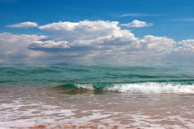 Bulutlu, güneşli bir gökyüzünün altında güzel bir sahil.