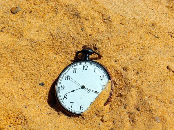 an antique pocket watch lies in the sand as part of a shipwreck and loss