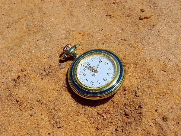 an antique pocket watch lies in the sand as part of a shipwreck and loss
