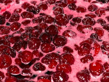 Ateş üstünde pişerken kiraz reçeli yüzeyinde köpük kaynıyor.