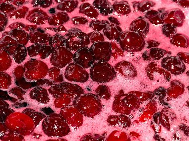 Ateş üstünde pişerken kiraz reçeli yüzeyinde köpük kaynıyor.