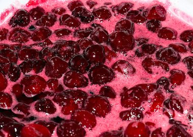 Ateş üstünde pişerken kiraz reçeli yüzeyinde köpük kaynıyor.