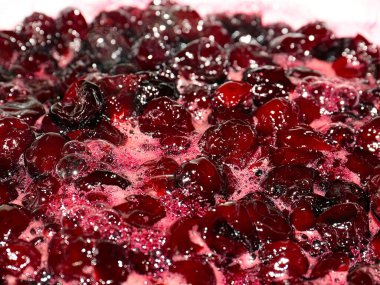 Ateş üstünde pişerken kiraz reçeli yüzeyinde köpük kaynıyor.