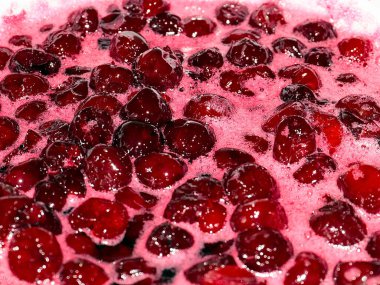 Ateş üstünde pişerken kiraz reçeli yüzeyinde köpük kaynıyor.