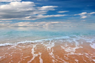 Güzel dalgalar ve deniz sahilleri Bulutlu yaz güneşinin altında