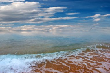 Güzel dalgalar ve deniz sahilleri Bulutlu yaz güneşinin altında