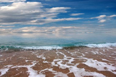 Güzel dalgalar ve deniz sahilleri Bulutlu yaz güneşinin altında