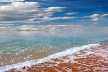 Güzel dalgalar ve deniz sahilleri Bulutlu yaz güneşinin altında