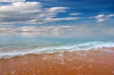 Güzel dalgalar ve deniz sahilleri Bulutlu yaz güneşinin altında