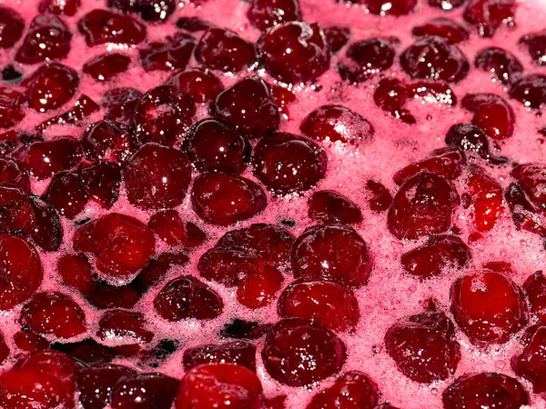 Ateş üstünde pişerken kiraz reçeli yüzeyinde köpük kaynıyor.