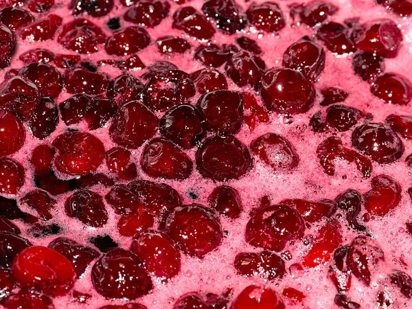 Ateş üstünde pişerken kiraz reçeli yüzeyinde köpük kaynıyor.