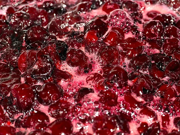 Ateş üstünde pişerken kiraz reçeli yüzeyinde köpük kaynıyor.