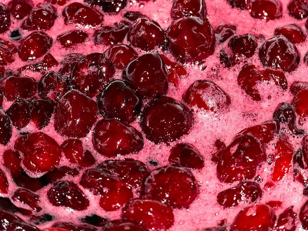 Ateş üstünde pişerken kiraz reçeli yüzeyinde köpük kaynıyor.