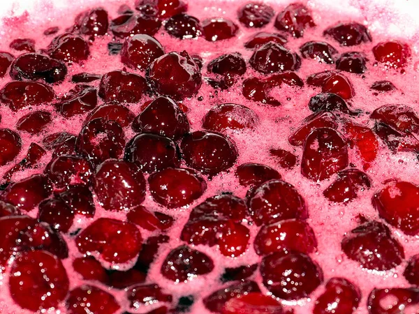 Ateş üstünde pişerken kiraz reçeli yüzeyinde köpük kaynıyor.