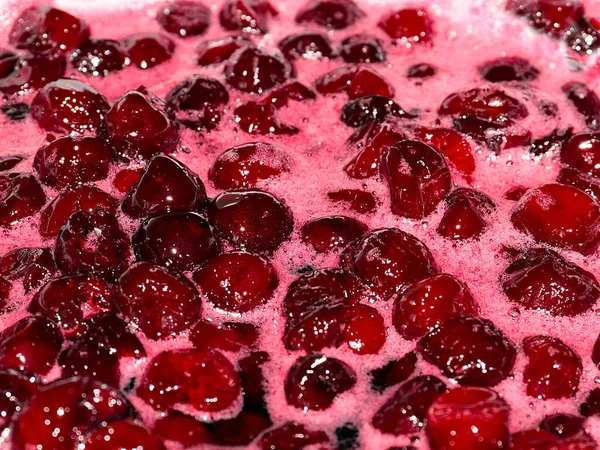 Ateş üstünde pişerken kiraz reçeli yüzeyinde köpük kaynıyor.