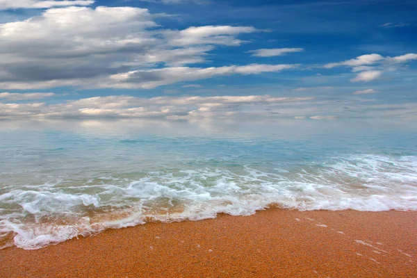 Güzel dalgalar ve deniz sahilleri Bulutlu yaz güneşinin altında