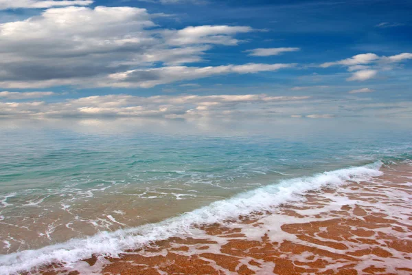 Güzel dalgalar ve deniz sahilleri Bulutlu yaz güneşinin altında