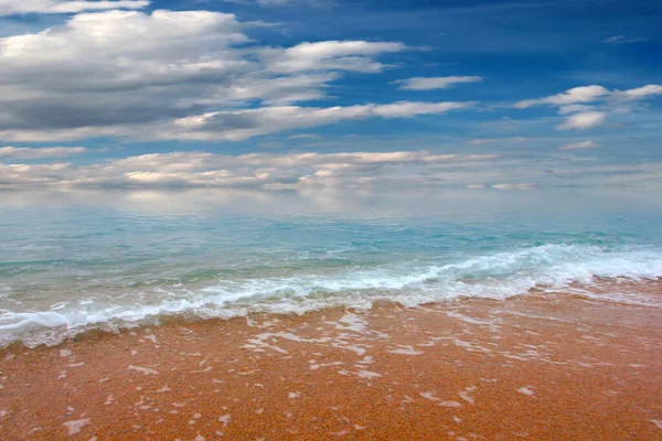 Güzel dalgalar ve deniz sahilleri Bulutlu yaz güneşinin altında