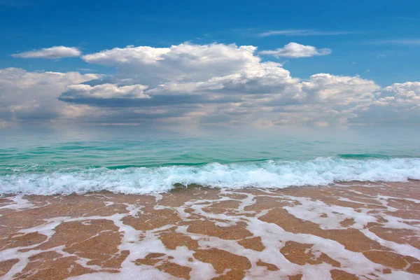 Güzel dalgalar ve deniz sahilleri Bulutlu yaz güneşinin altında
