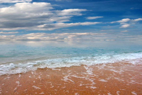 Güzel dalgalar ve deniz sahilleri Bulutlu yaz güneşinin altında