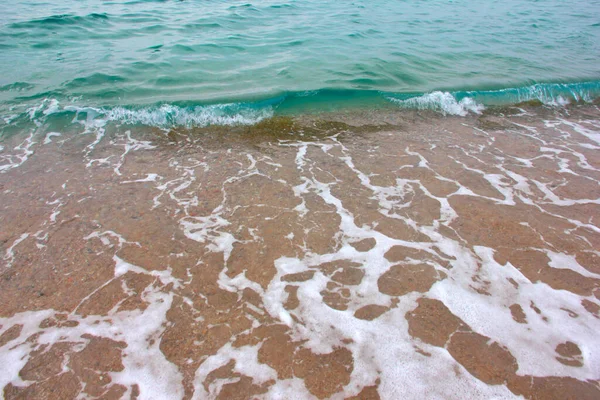 海浪表面和海滩沙滩上的泡沫和气泡 — 图库照片