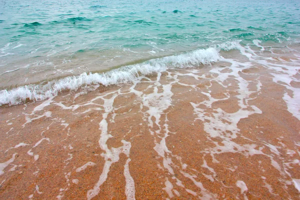 海の波と砂浜の表面に泡と気泡があります — ストック写真