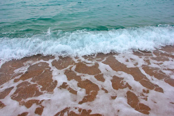 海の波と砂浜の表面に泡と気泡があります — ストック写真