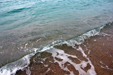 Açık deniz dalgaları ve aktif bir dinlenme yeri olarak güneşli bir kumsal.
