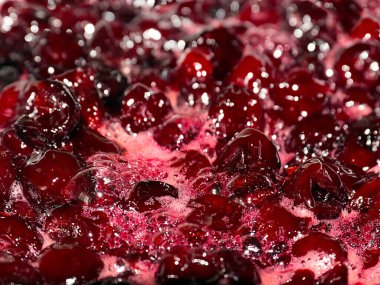 Yemek pişirirken kiraz reçelinin yüzeyinde hava kabarcıkları ve tatlı köpük var.