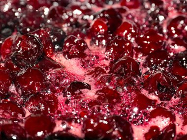 Yemek pişirirken kiraz reçelinin yüzeyinde hava kabarcıkları ve tatlı köpük var.