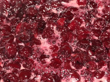 Yemek pişirirken kiraz reçelinin yüzeyinde hava kabarcıkları ve tatlı köpük var.