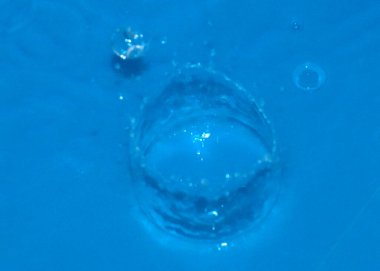 Bir damla temiz su tarafından vurulduktan sonra sıvının yüzeyindeki zarif desenler.