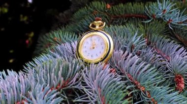Altın bir çantanın içindeki antika saat bir Noel ağacının dalında yatıyor.
