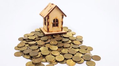 Ahşap bir ev, metal ruble yığını üzerinde duruyor ve kağıt gagalar düşüyor.