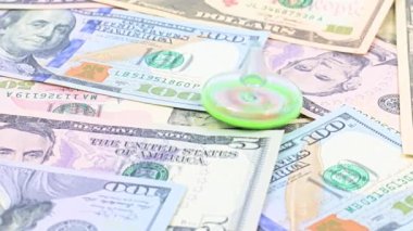 Bir plastik fırıldak, ticaret sisteminin dengesi için bir sembol olarak Amerikan doları banknotları yığını üzerinde döner