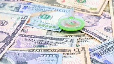 Bir plastik fırıldak, ticaret sisteminin dengesi için bir sembol olarak Amerikan doları banknotları yığını üzerinde döner