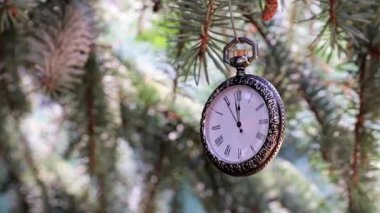 Yılbaşı ağacı dalında asılı antika bir cep saati.
