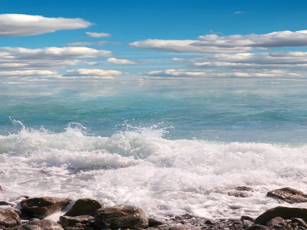 小石や波が立ち並ぶ美しい海の上の晴れ渡った空 — ストック写真