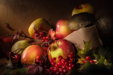 Koyu ahşap bir arka planda, kumaş bir çantada elmalar.