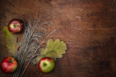 Elmalar, kuru kulaklar ve koyu ahşap arka planda yapraklar. Sonbahar stili.