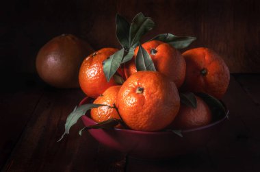 Kaba bir kumaş üzerinde koyu kırsal bir tarzda mandalinalar.