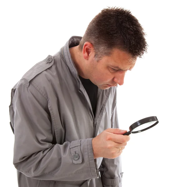 Man with raincoat is looking with magnifying glass — Stock Photo, Image