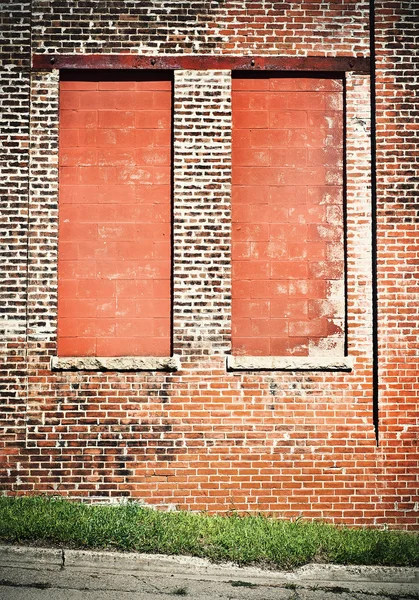 Two windows in a brick building boarded up with cinder blocks — Stock Photo, Image