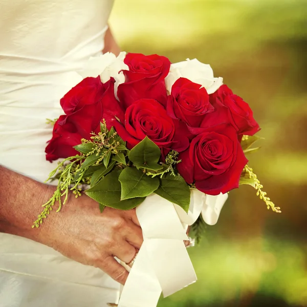 Bride holding red rose bouquet — Stock Photo, Image