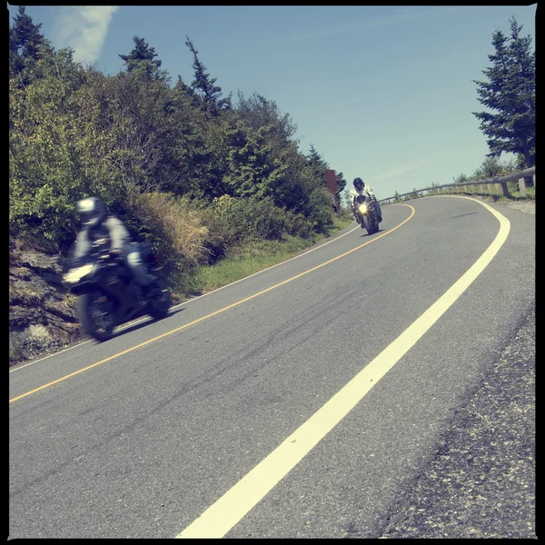Motociclistas descendo uma estrada de montanha pavimentada — Fotografia de Stock